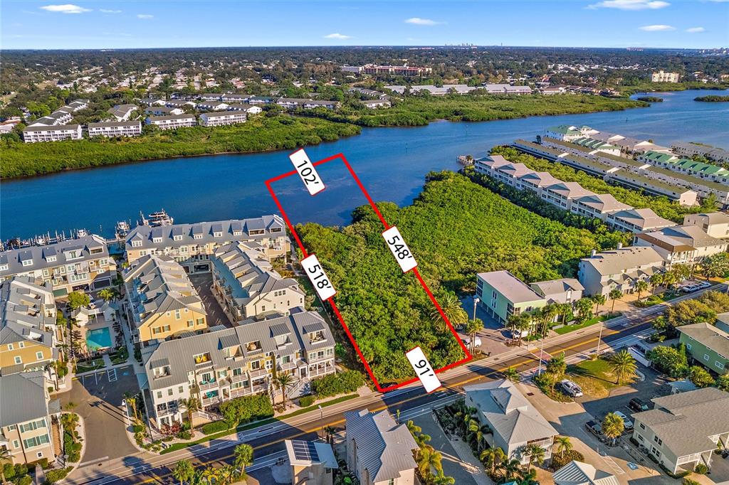 This aerial view shows a vacant, rectangular waterfront lot outlined in red near residential buildings — 19901 GULF BLVD, INDIAN SHORES, FL