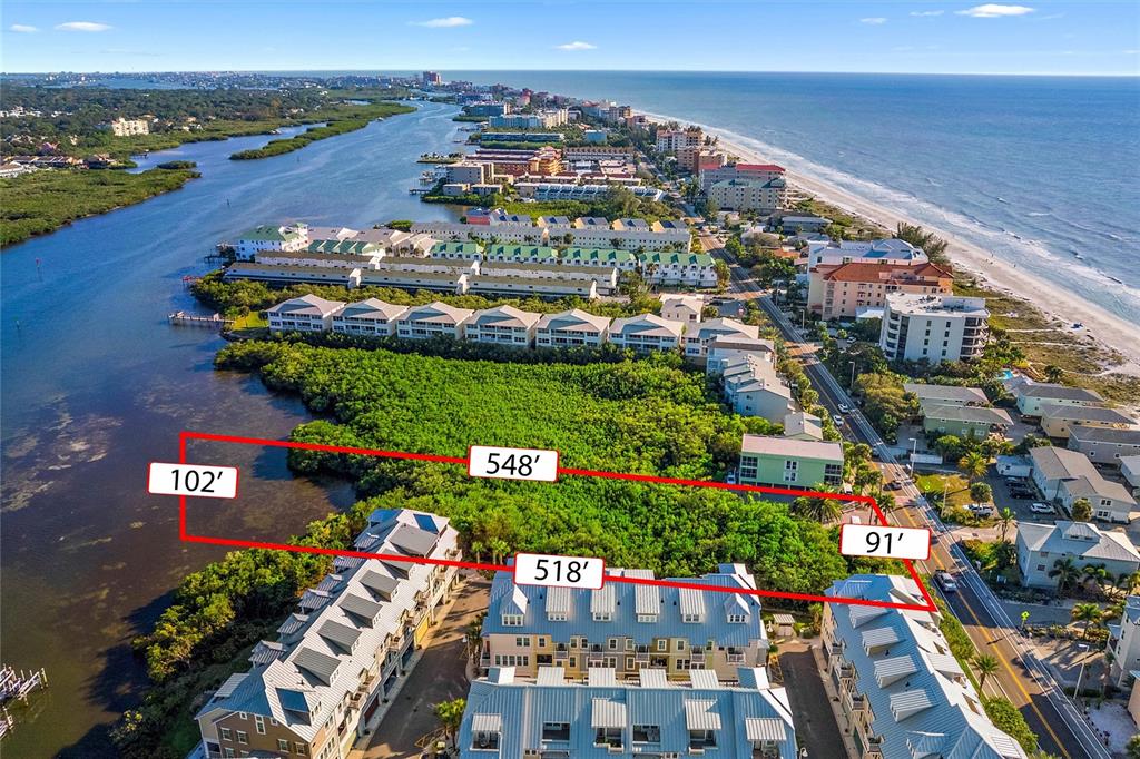 An aerial view shows a vacant, rectangular waterfront lot outlined in red near residential buildings — 19901 GULF BLVD, INDIAN SHORES, FL