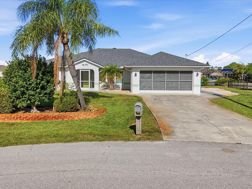 A single-story house with a gray roof, a screened garage, and a palm tree — 18350 VAN NUYS CIRCLE, PORT CHARLOTTE, FL