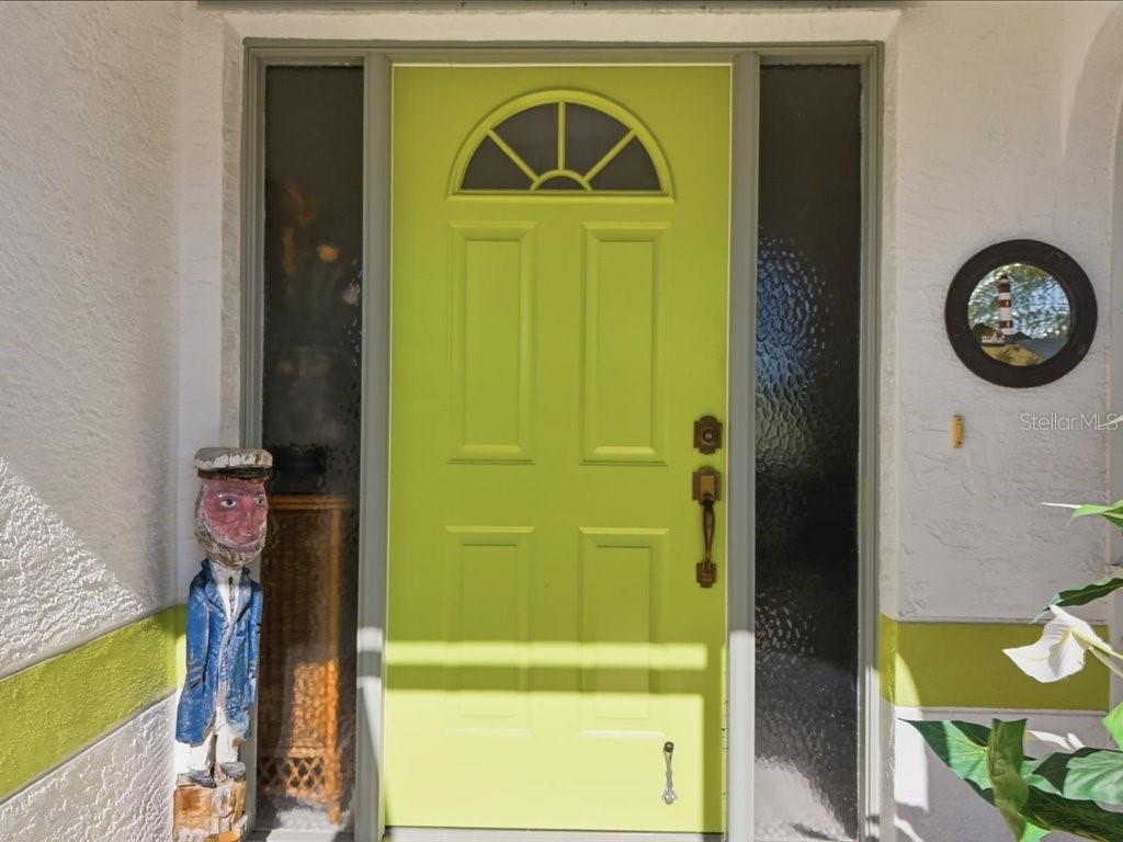 A bright lime green front door with a side light and a decorative wooden statue — 18350 VAN NUYS CIRCLE, PORT CHARLOTTE, FL