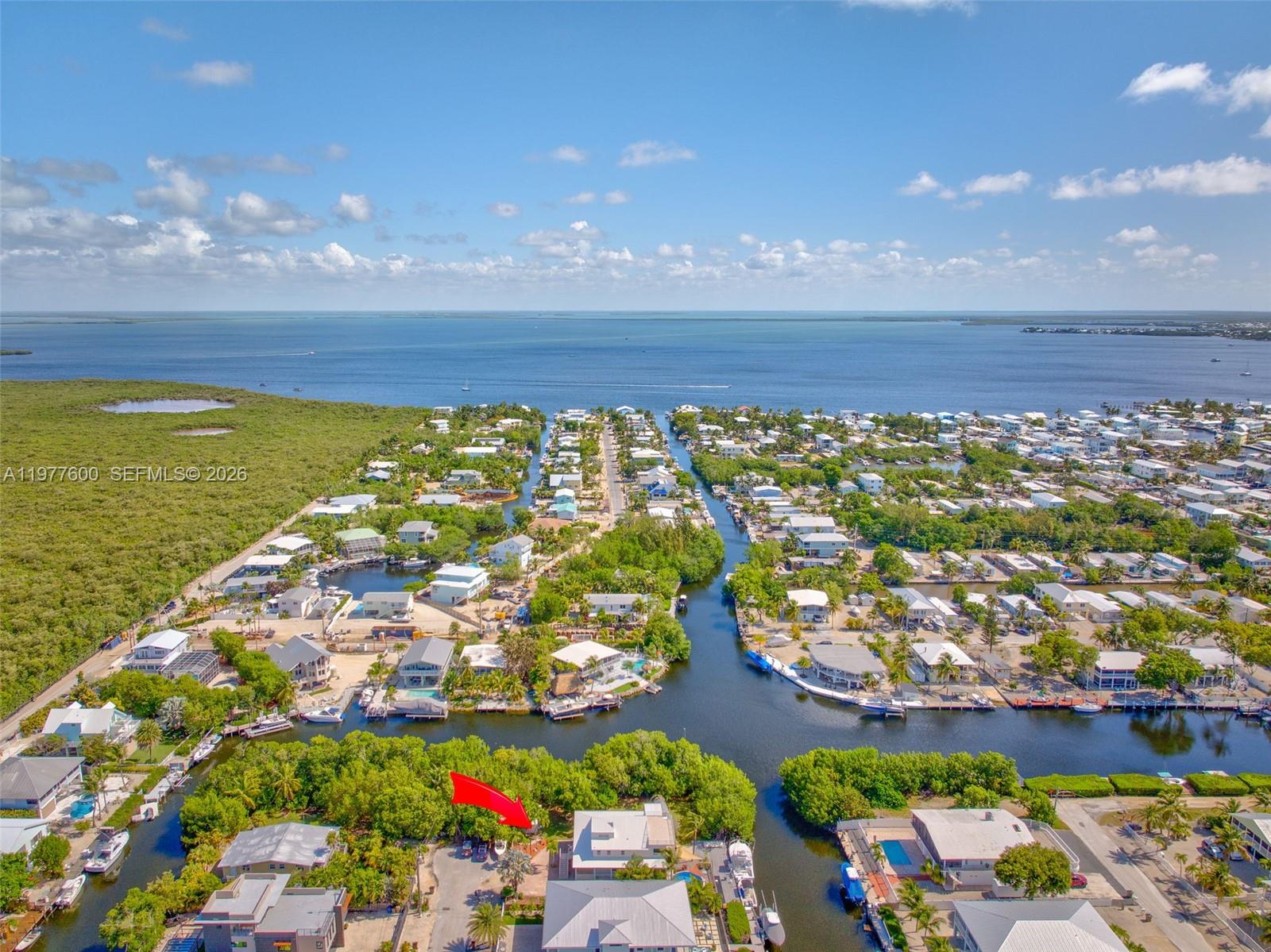 An aerial view shows waterfront homes along canals leading to a large open bay — 894 Ellen Dr, Key Largo FL 33037, KEY LARGO, FL
