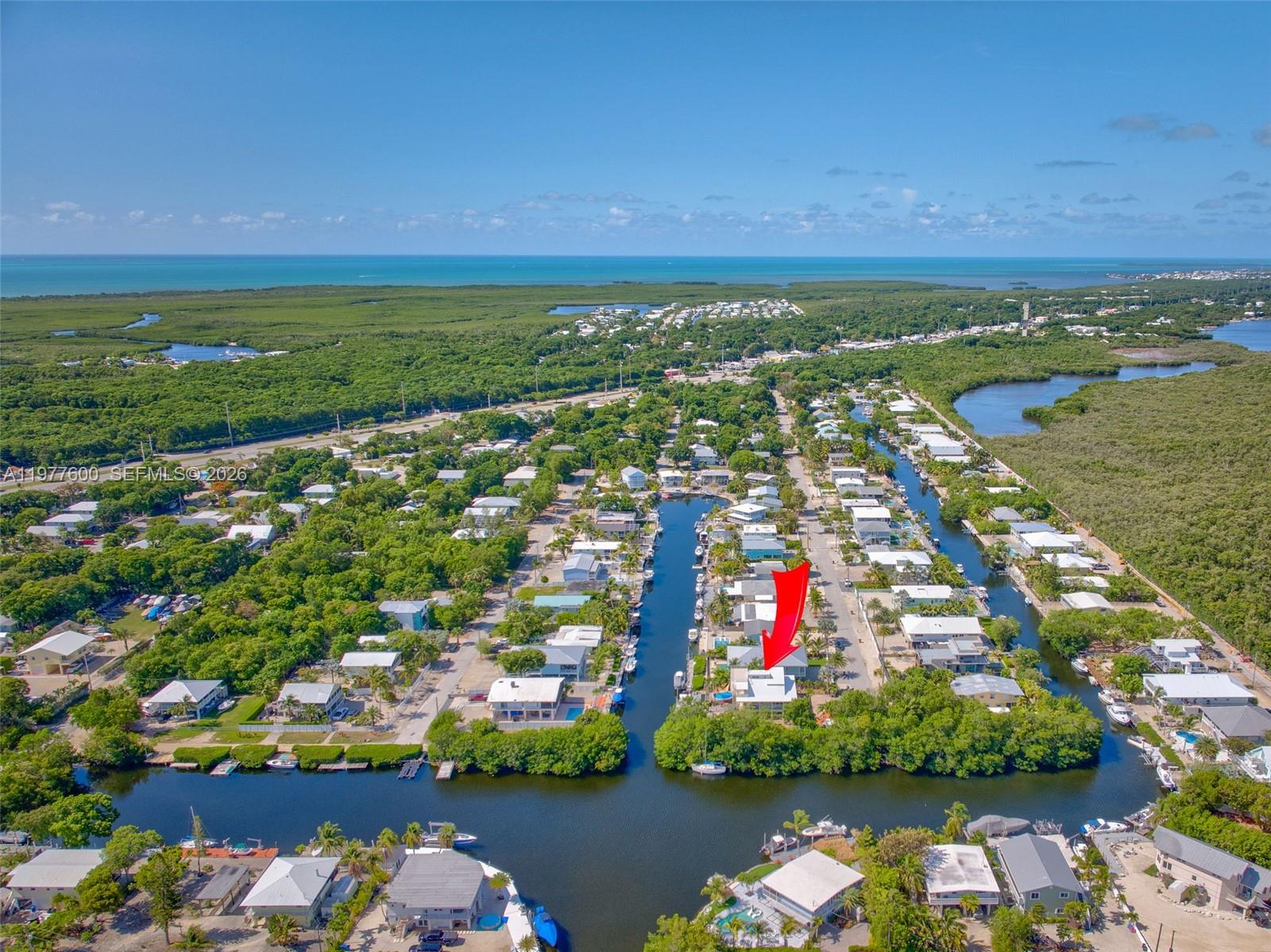 An aerial view shows a waterfront house with a red arrow pointing to it — 894 Ellen Dr, Key Largo FL 33037, KEY LARGO, FL