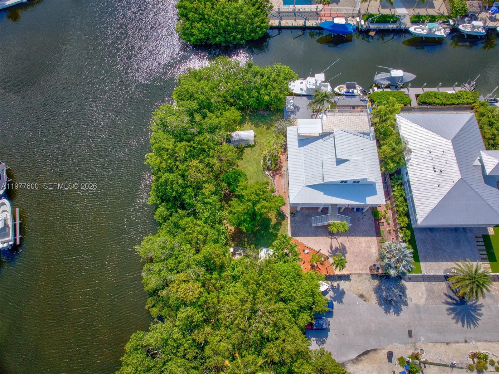 An aerial view shows a waterfront house with a metal roof and a boat dock — 894 Ellen Dr, Key Largo FL 33037, KEY LARGO, FL