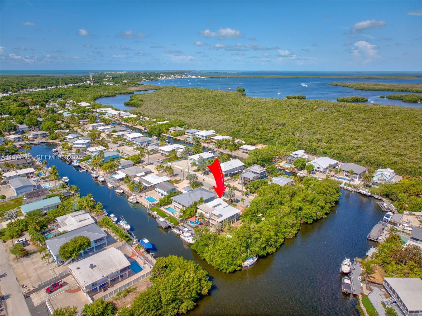 An aerial view shows a waterfront house with a red arrow pointing toward it — 894 Ellen Dr, Key Largo FL 33037, KEY LARGO, FL