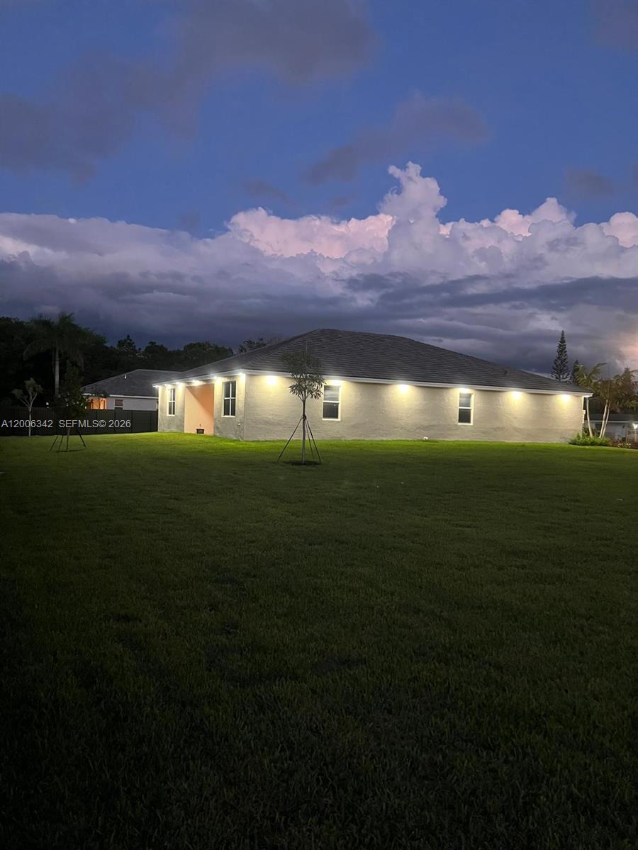 The exterior of a single-story house with illuminated soffit lights at dusk — 17775 SW 296th St, Homestead FL 33030, HOMESTEAD, FL