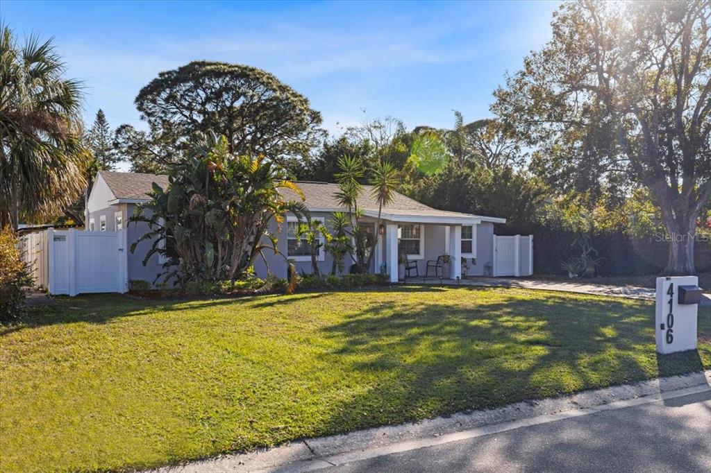 A single-story gray house with a covered porch sits behind a grassy front lawn — 4106 W BAY VIEW AVENUE, TAMPA, FL