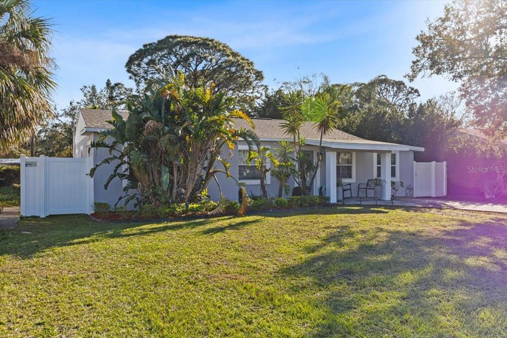 A single-story house with a gray exterior, a front porch, and lush landscaping — 4106 W BAY VIEW AVENUE, TAMPA, FL