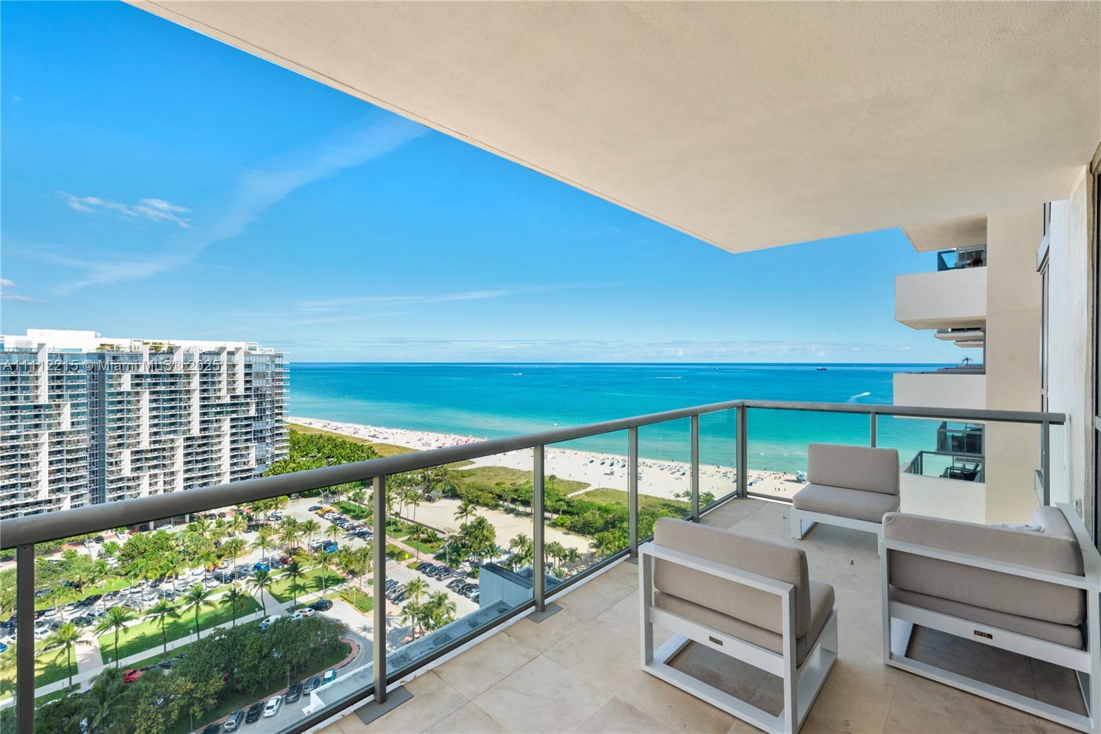 A balcony with two chairs overlooks a beach, ocean, and a parking lot — 101 20th St # 2401, Miami Beach FL 33139, MIAMI BEACH, FL