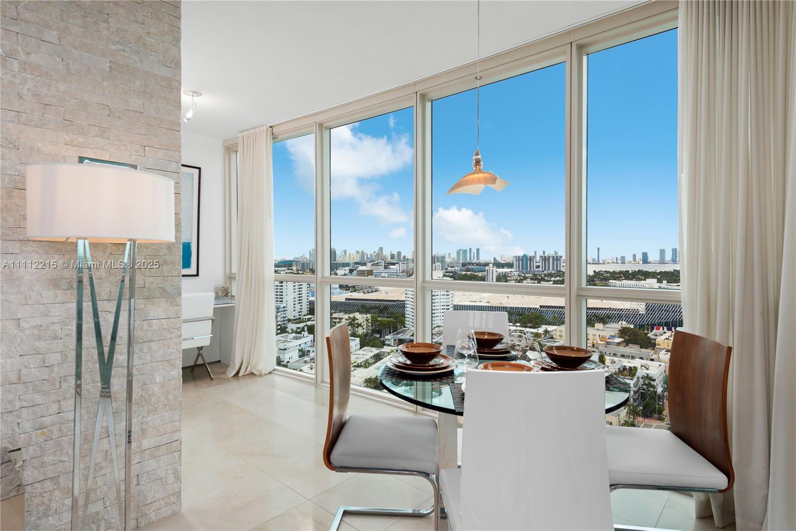 A dining area with a glass table and city views through floor-to-ceiling windows — 101 20th St # 2401, Miami Beach FL 33139, MIAMI BEACH, FL
