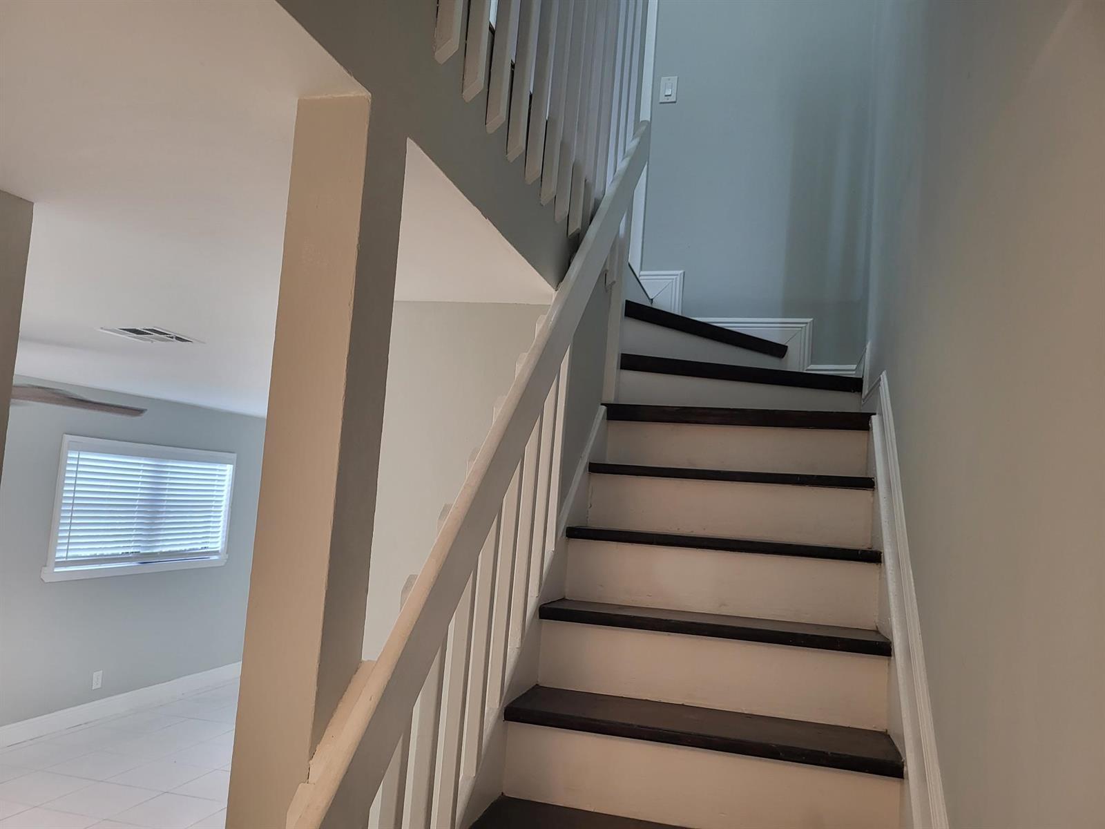 A staircase with dark wooden treads and white risers leads to an upper level — 4135 NE 21st Terrace, Lighthouse Point FL 33064, LIGHTHOUSE POINT, FL