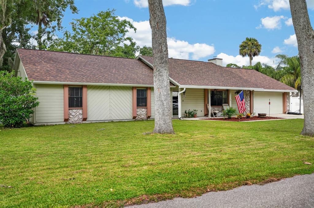 A single-story house with light-colored siding, a brown shingled roof, and an American flag — 105 EDDY LANE, PORT ORANGE, FL