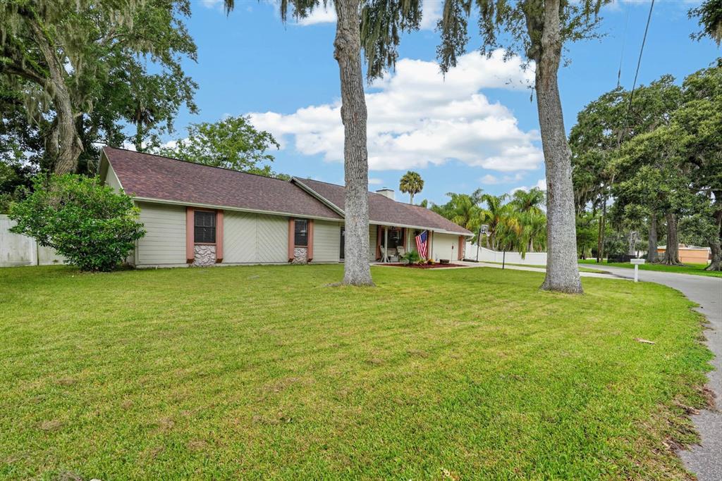 A single-story house with light-colored siding, a brown shingled roof, and large trees in front — 105 EDDY LANE, PORT ORANGE, FL