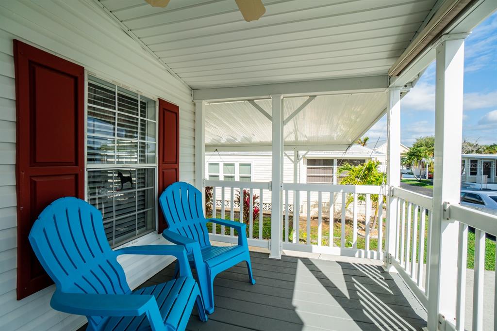 Two blue Adirondack chairs sit on a covered porch with white railings and siding — 10303 BURNT STORE ROAD UNIT 203, PUNTA GORDA, FL