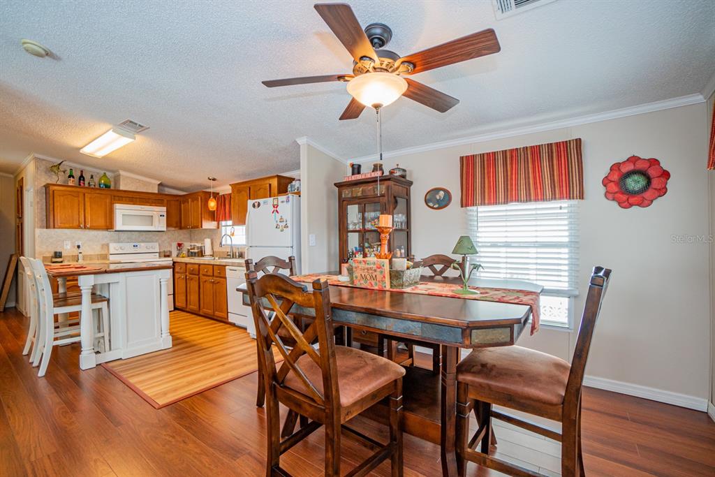 A kitchen and dining area featuring wooden cabinets, a ceiling fan, and a dining table — 10303 BURNT STORE ROAD UNIT 203, PUNTA GORDA, FL