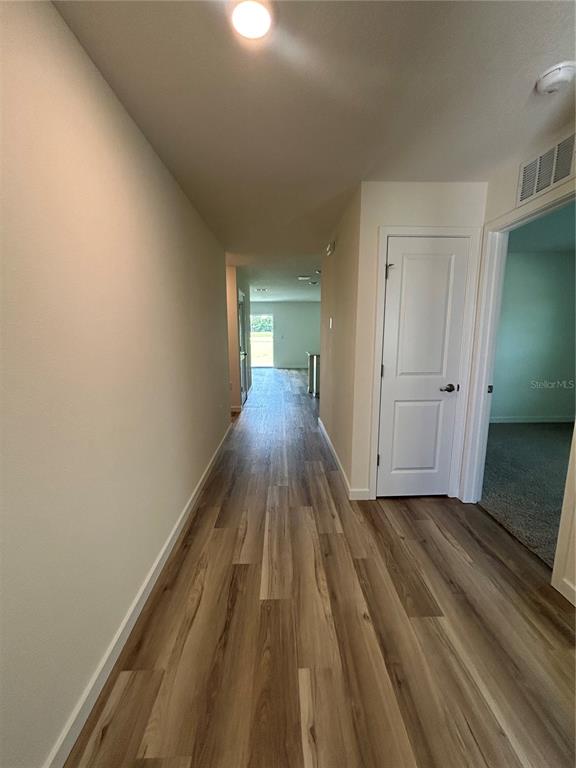 A hallway with wood-look flooring leads toward an open living area with a closed door — 13145 SW 58 COURT, OCALA, FL