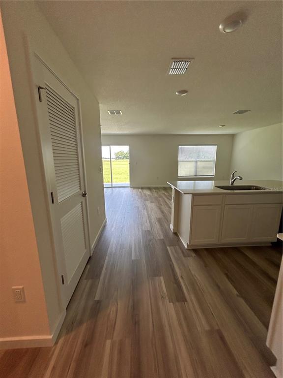 An open-concept kitchen and living area features light wood-look flooring and a white island — 13145 SW 58 COURT, OCALA, FL