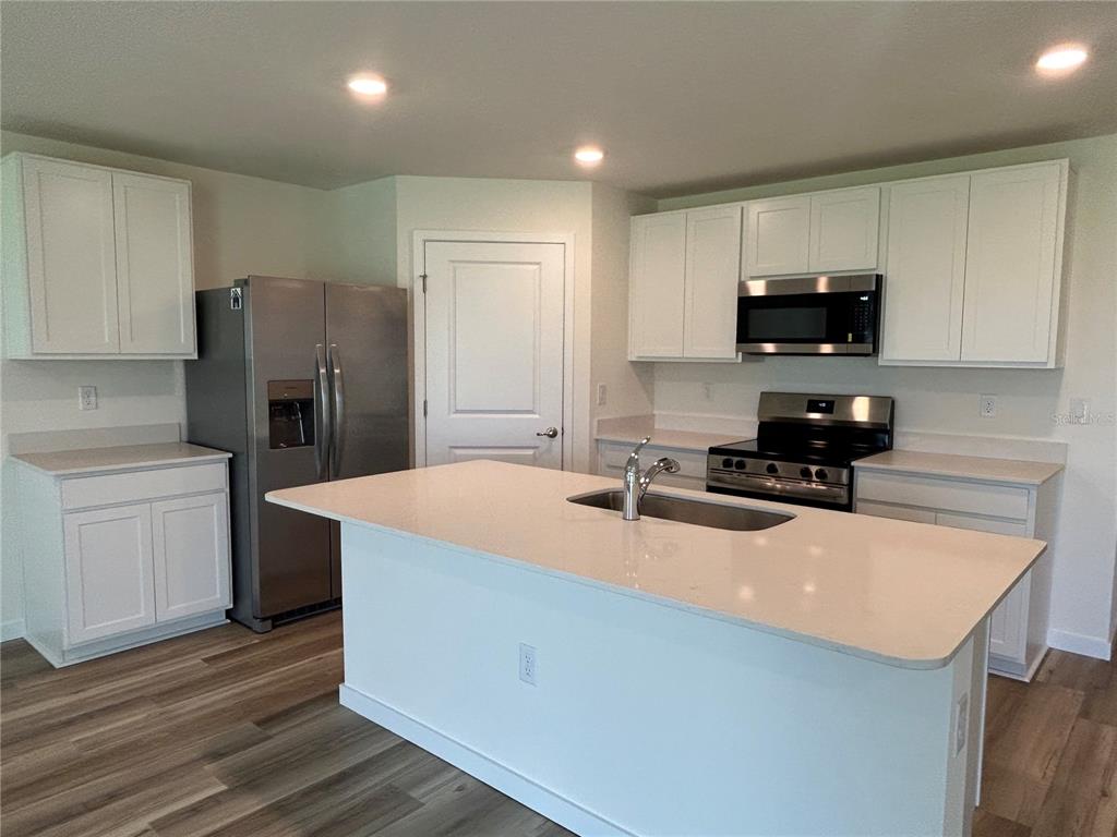 A modern kitchen features white cabinetry, stainless steel appliances, and a large central island — 13145 SW 58 COURT, OCALA, FL