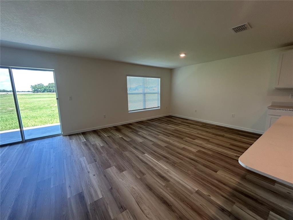 An open-concept living area features wood-look flooring, a sliding glass door, and a kitchen counter — 13145 SW 58 COURT, OCALA, FL