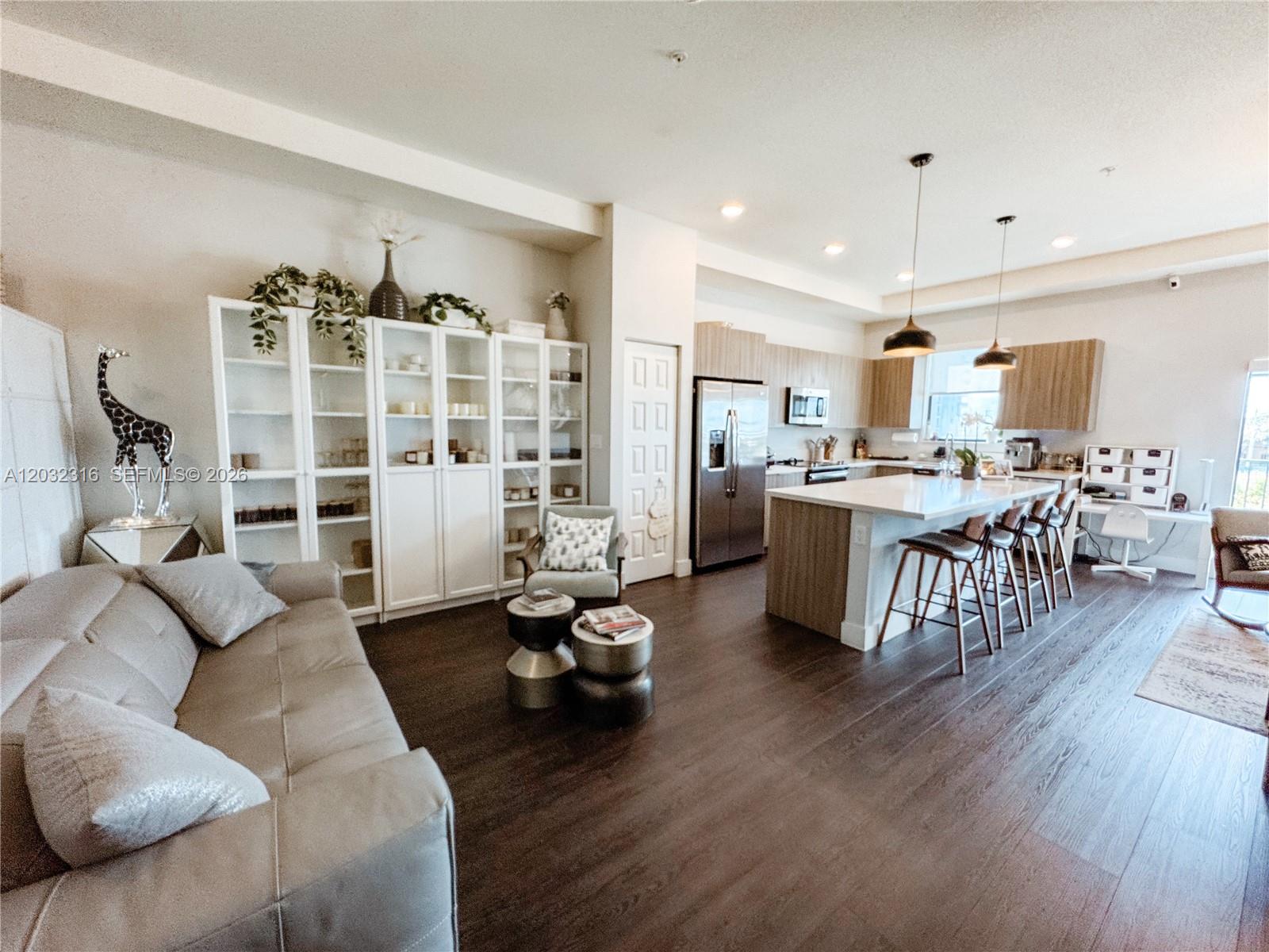 An open-concept living room and kitchen feature dark wood floors, white cabinetry, and an island — 10455 NW 82nd St # 32, Doral FL 33178, DORAL, FL