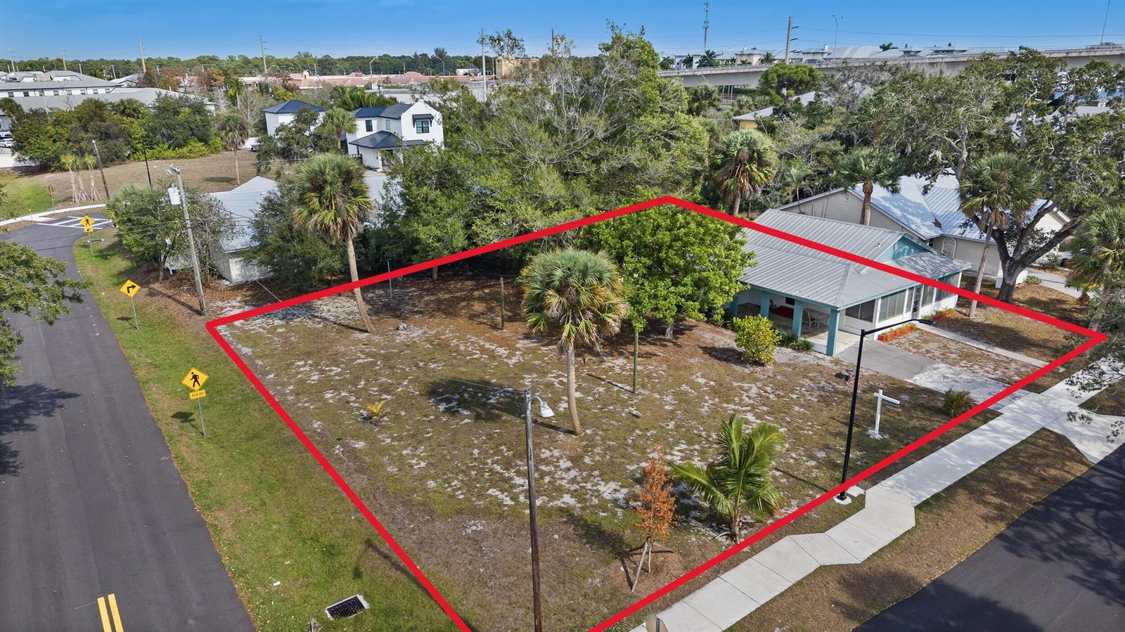 An aerial view shows a vacant, grassy corner lot with several palm trees and a house — 621 NW Australian Street, Stuart FL 34994, STUART, FL