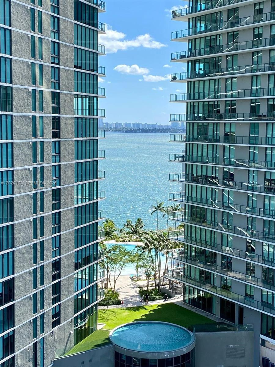 A view between two high-rise buildings looking out toward a bay, pool, and palm trees — 501 NE 31st St # 1201, Miami FL 33137, MIAMI, FL