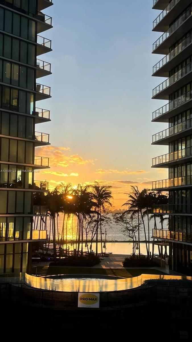 A sunset view between two modern high-rise buildings overlooking a pool and the water — 501 NE 31st St # 1201, Miami FL 33137, MIAMI, FL