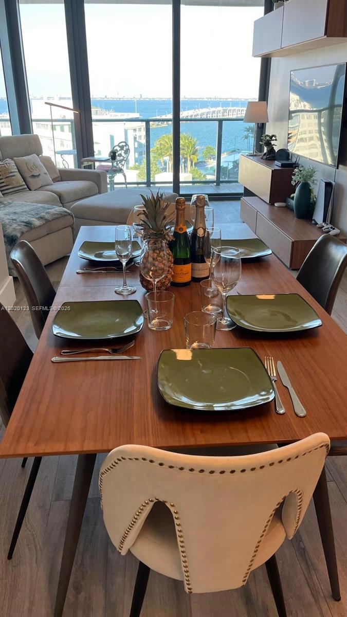 A dining room with a wooden table, green plates, and a view of the ocean — 501 NE 31st St # 1201, Miami FL 33137, MIAMI, FL
