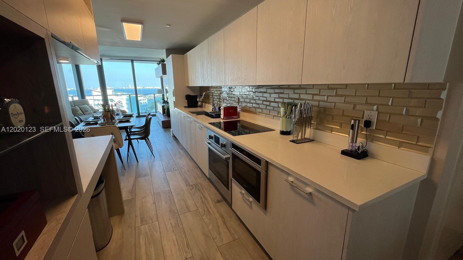 A modern galley kitchen features light wood cabinets, white countertops, and a subway tile backsplash — 501 NE 31st St # 1201, Miami FL 33137, MIAMI, FL