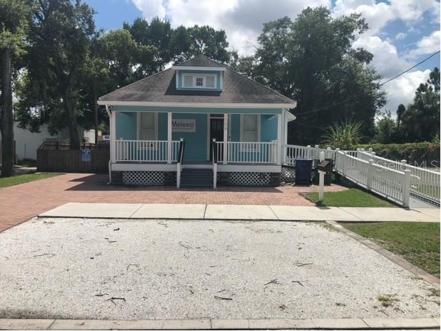 A light blue bungalow with a front porch, brick driveway, and a white accessibility ramp — 106 W EUCLID AVENUE, TAMPA, FL