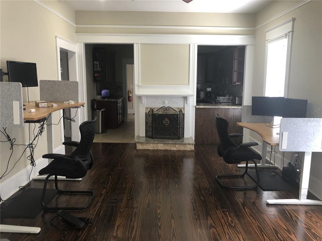 A room with dark hardwood floors, a fireplace, and two standing desks with office chairs — 106 W EUCLID AVENUE, TAMPA, FL