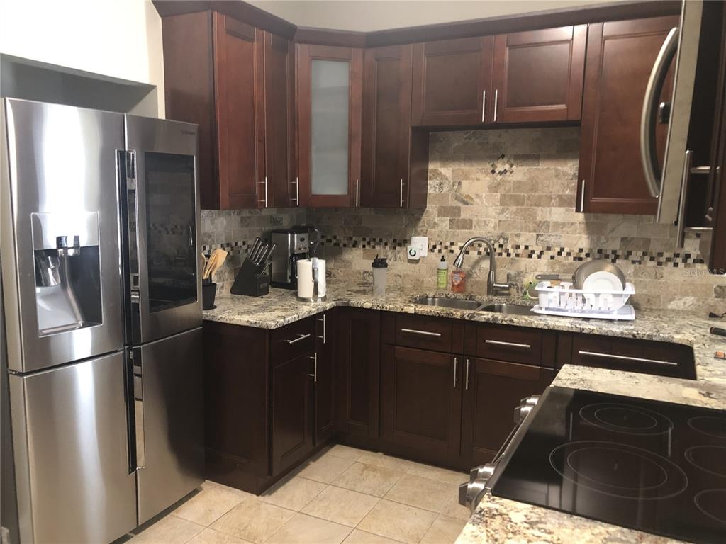 A kitchen featuring dark wood cabinets, granite countertops, stainless steel appliances, and a tiled backsplash — 106 W EUCLID AVENUE, TAMPA, FL