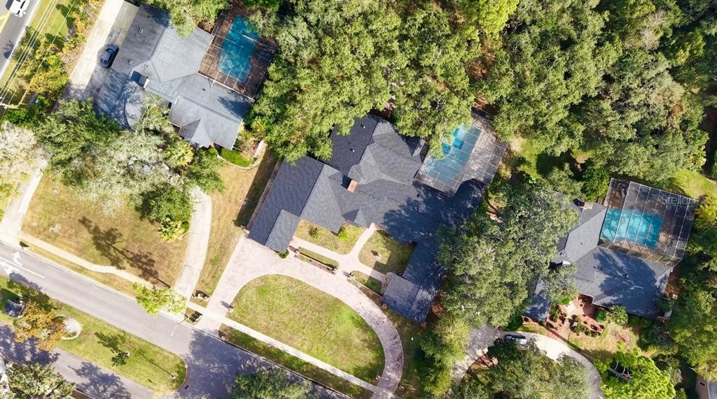 An aerial view shows three houses with swimming pools surrounded by trees and paved driveways — 201 S SWEETWATER COVE BOULEVARD, LONGWOOD, FL