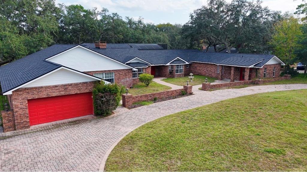 An aerial view of a single-story brick house with a red garage door and driveway — 201 S SWEETWATER COVE BOULEVARD, LONGWOOD, FL