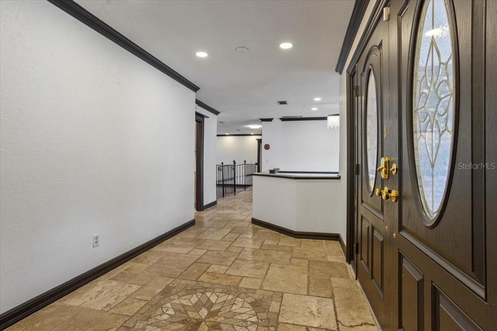 An entryway features tile flooring with a decorative medallion, dark wood doors, and crown molding — 201 S SWEETWATER COVE BOULEVARD, LONGWOOD, FL