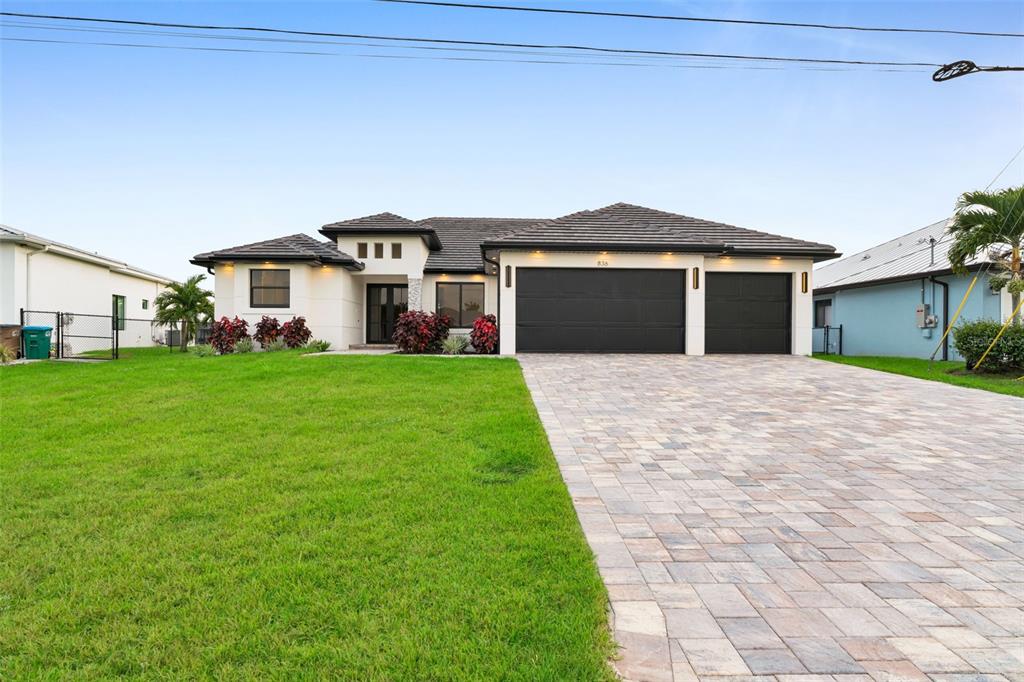 A single-story house with a tiled roof, black garage doors, and a paved driveway — 836 SW 36TH TERRACE, CAPE CORAL, FL