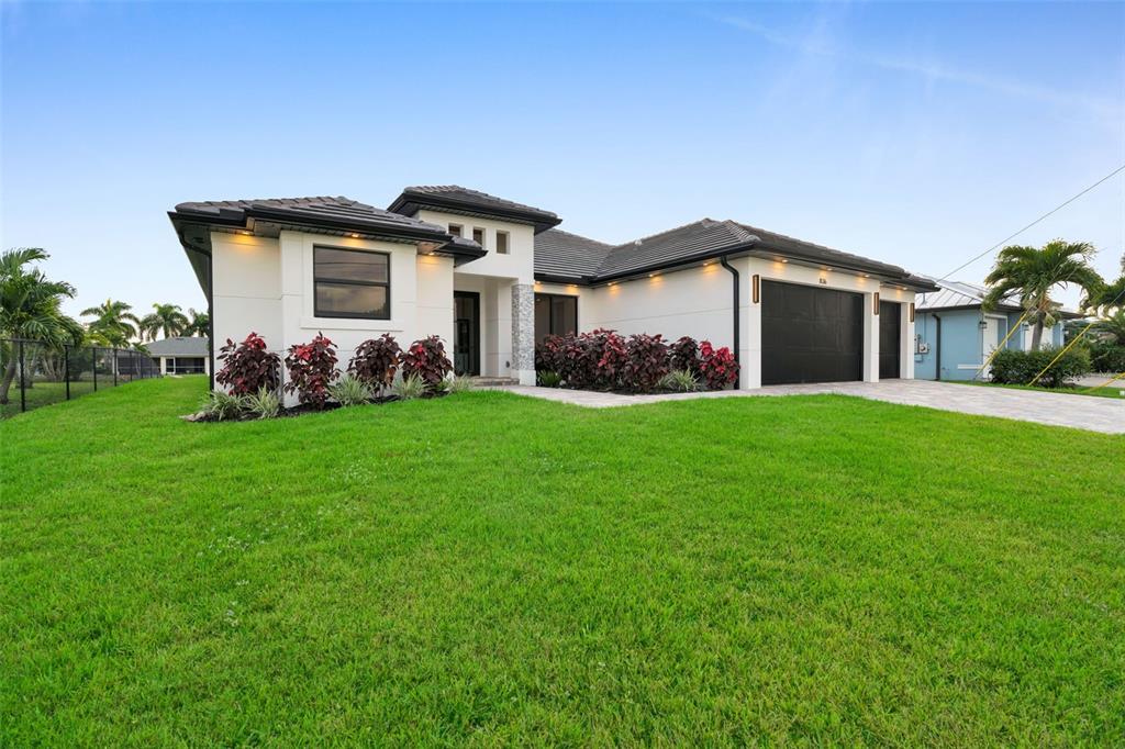 A modern, single-story house with a white exterior, dark roof, and a two-car garage — 836 SW 36TH TERRACE, CAPE CORAL, FL