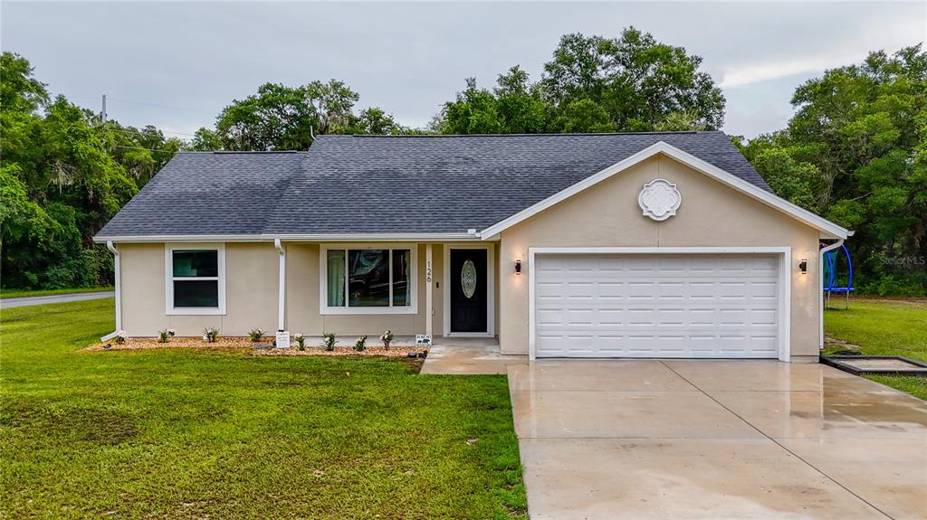 A single-story house with a beige exterior, dark roof, and an attached two-car garage — 126 LOCUST RADIAL, OCALA, FL