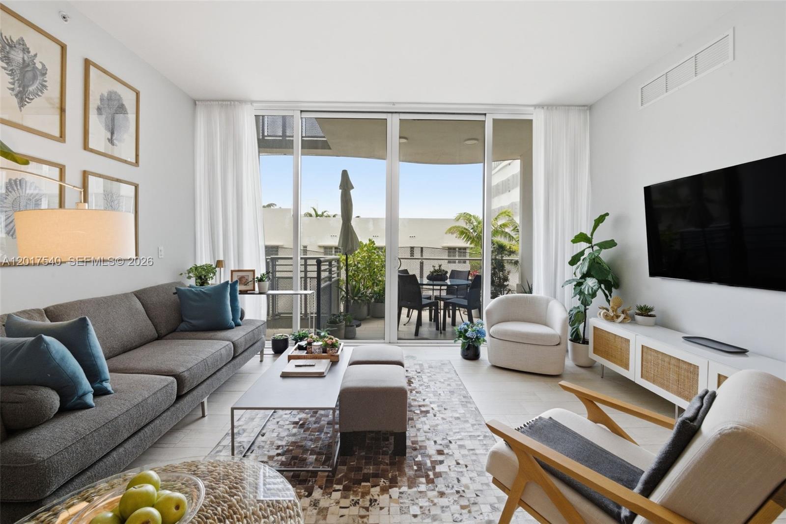 A bright living room features a gray sofa, modern furniture, and a balcony with seating — 2100 Park Ave # 302, Miami Beach FL 33139, MIAMI BEACH, FL