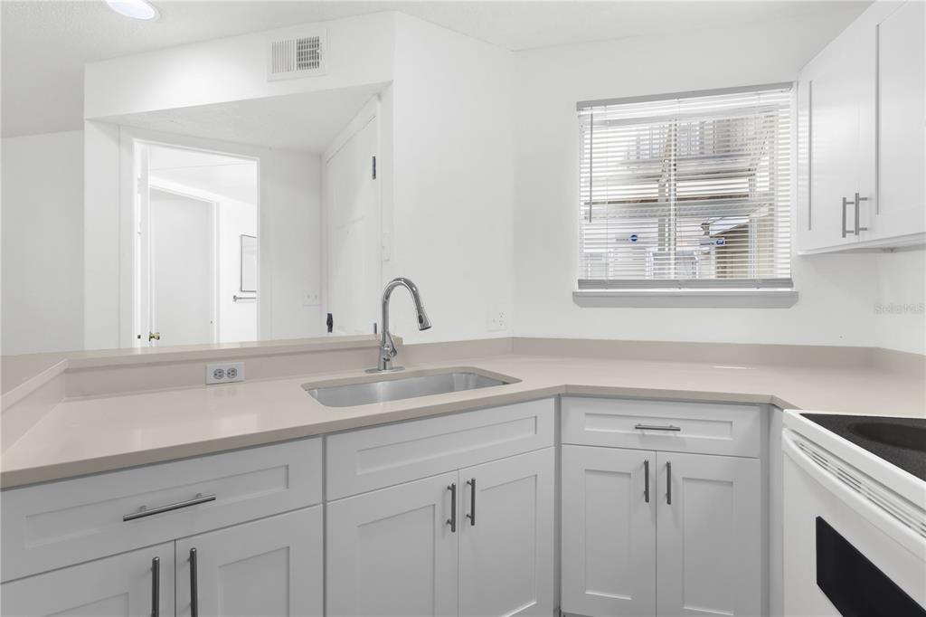 A kitchen features white cabinets, light countertops, a stainless steel sink, and a window — 1964 LAKE ATRIUMS CIRCLE UNIT 170, ORLANDO, FL