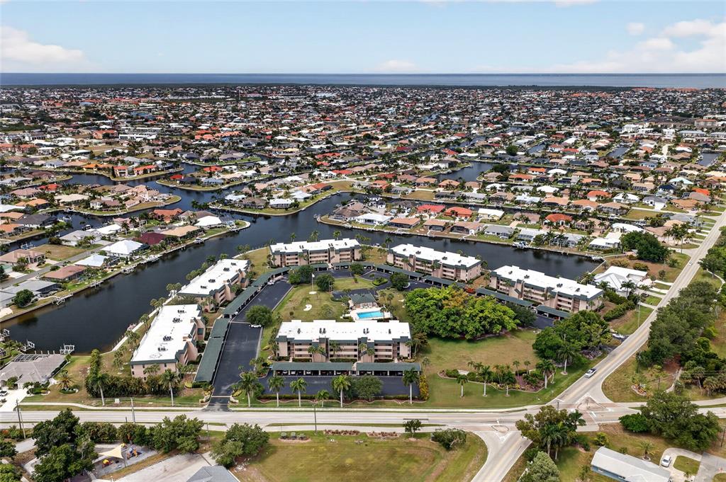 An aerial view shows a multi-building apartment complex surrounded by residential canals and streets — 601 SHREVE STREET UNIT 51C, PUNTA GORDA, FL