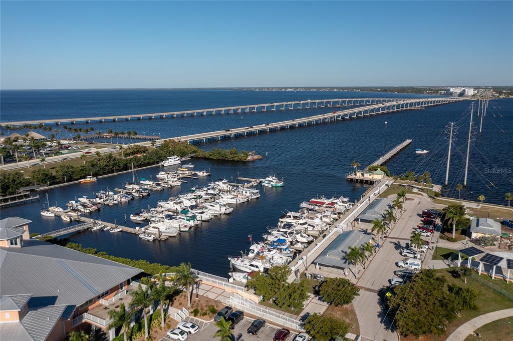 An aerial view shows a marina with docked boats next to a long bridge — 601 SHREVE STREET UNIT 51C, PUNTA GORDA, FL