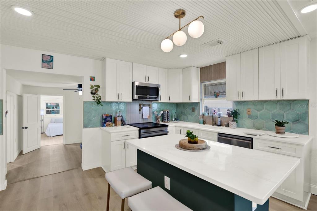 A kitchen features white cabinets, a teal hexagonal tile backsplash, and a central island — 4828 6TH AVENUE S, ST PETERSBURG, FL