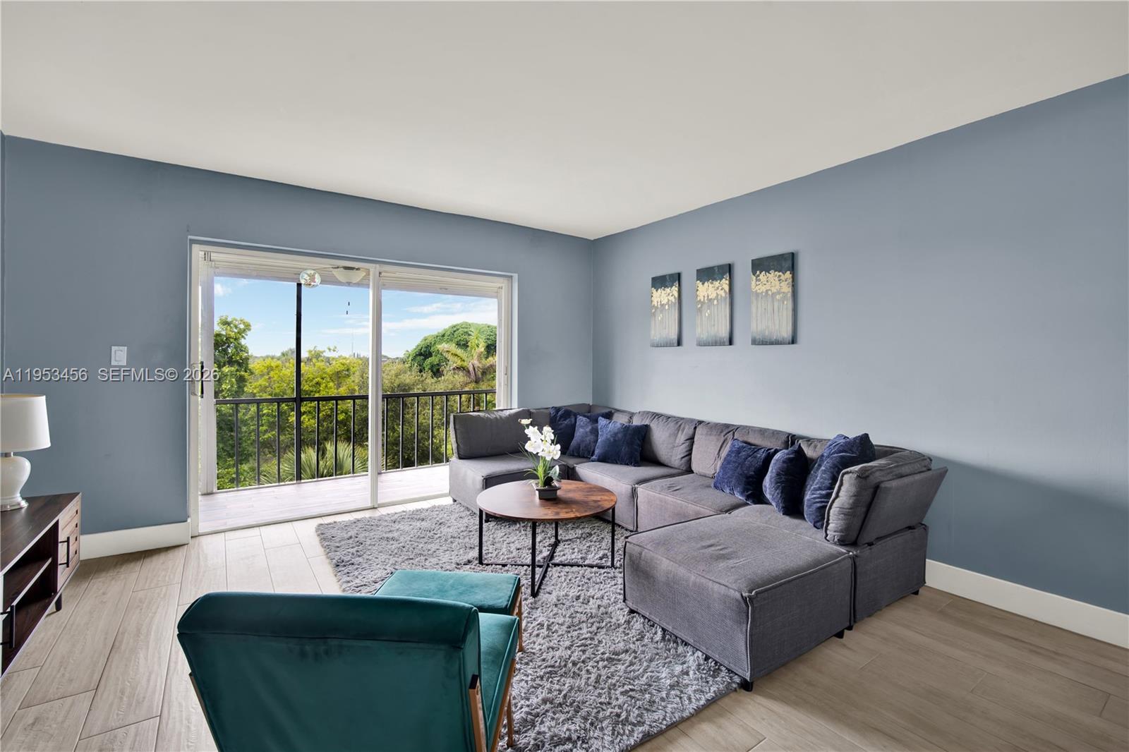 A living room features a gray sectional sofa, a teal armchair, and a balcony view — 950 Hillcrest Dr # 414, Hollywood FL 33021, HOLLYWOOD, FL