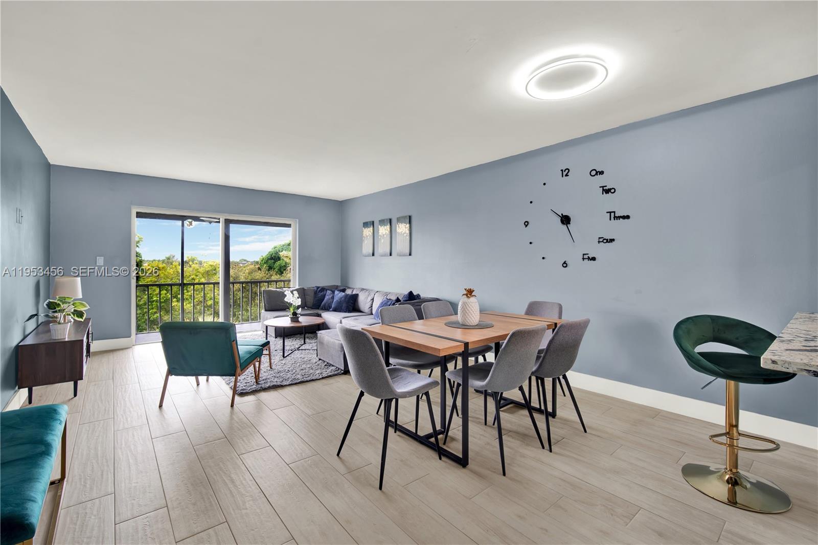 A living and dining area features light wood-look tile floors and a wall-mounted clock — 950 Hillcrest Dr # 414, Hollywood FL 33021, HOLLYWOOD, FL