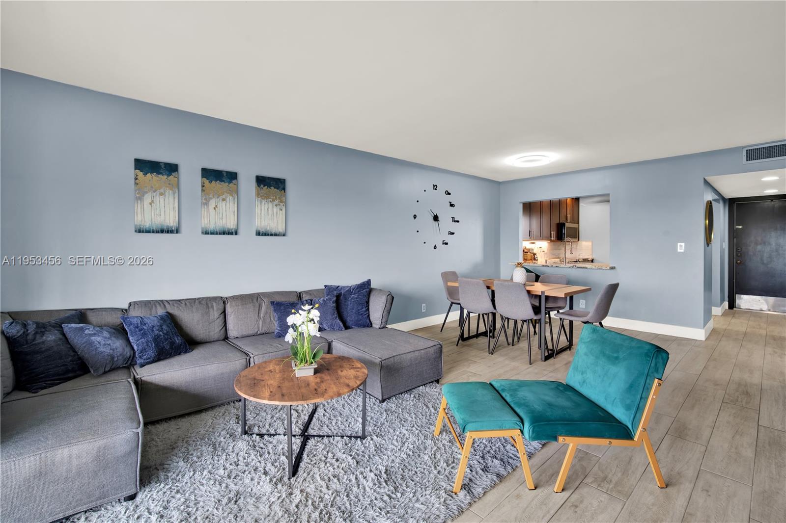 A living room features a gray sectional sofa, a teal chair, and a dining area — 950 Hillcrest Dr # 414, Hollywood FL 33021, HOLLYWOOD, FL