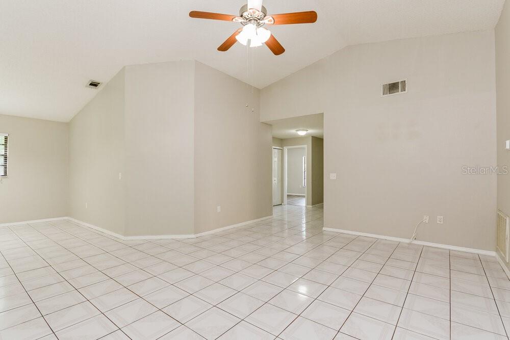 An empty room with light-colored tile flooring, beige walls, and a ceiling fan — 1657 SUNBURST WAY, KISSIMMEE, FL