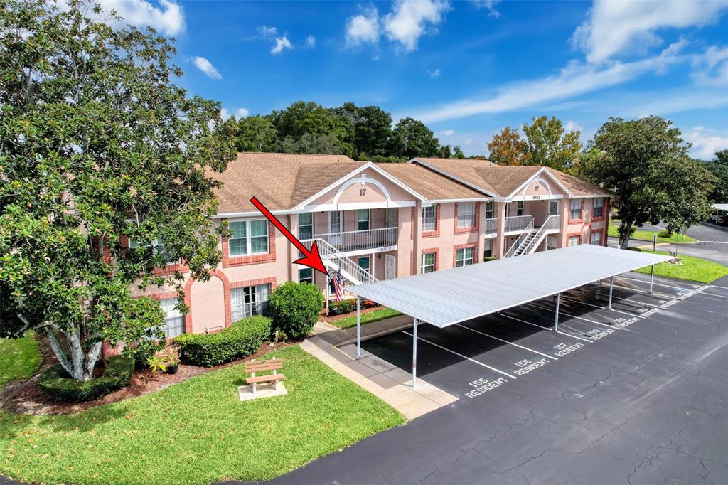 A two-story apartment building with a covered parking area and a red arrow pointing down — 6433 TINA DRIVE UNIT 12, NEW PORT RICHEY, FL