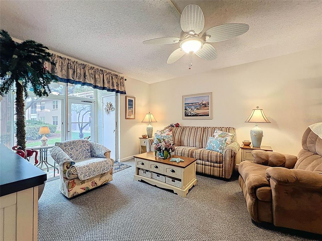 A living room features a striped sofa, a brown recliner, and a ceiling fan — 6433 TINA DRIVE UNIT 12, NEW PORT RICHEY, FL