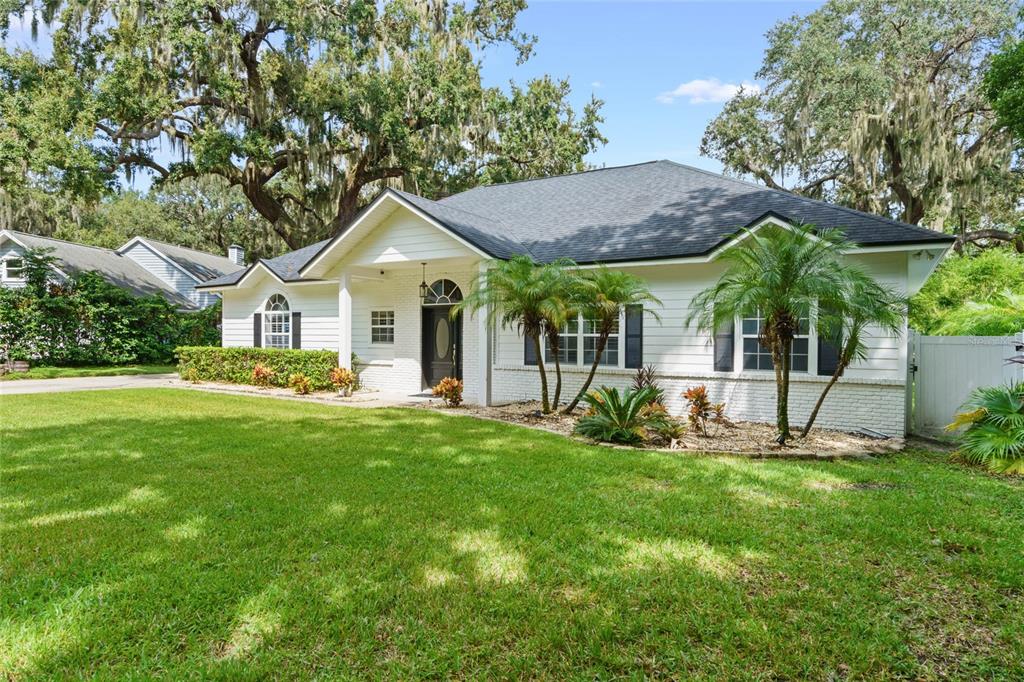 A white, single-story house with a dark roof and palm trees in the front yard — 715 MAGNOLIA STREET, WINDERMERE, FL