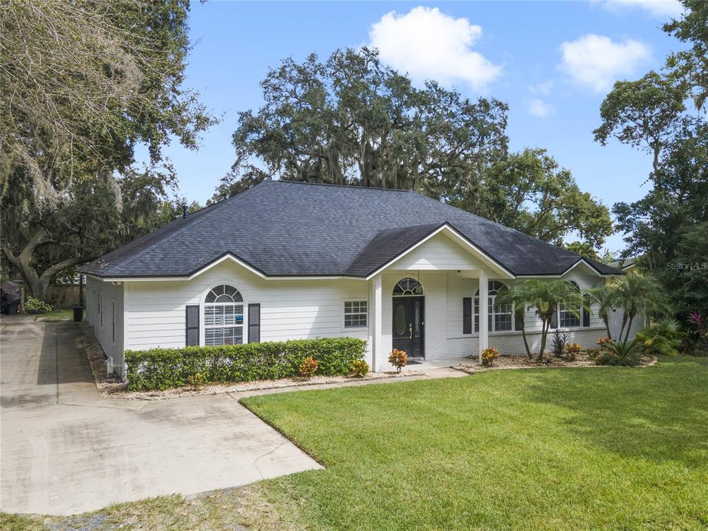 A white single-story house with a dark shingled roof, arched windows, and a concrete driveway — 715 MAGNOLIA STREET, WINDERMERE, FL